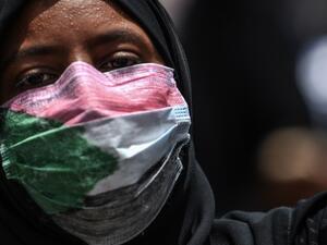 A masked Sudanese protester rallies outside the army complex in Sudan's capital Khartoum (AFP)
