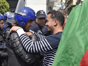 An Algerian man, embraces a member of the security forces during an anti government demonstration in the capital Algiers on April 23, 2019.  RYAD KRAMDI / AFP