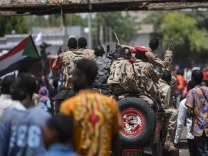 A Sudanese soldier flashes the victory sign at protesters during a sit-in outside the army headquarters in the capital Khartoum (AFP)