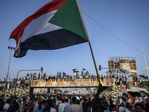 Sudanese protesters wave the national flag during a sit-in outside the army headquarters in the capital Khartoum  (AFP)