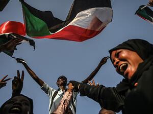 Sudanese protesters chant slogans and wave the national flag during a sit-in outside the army headquarters in the capital Khartoum  (AFP)