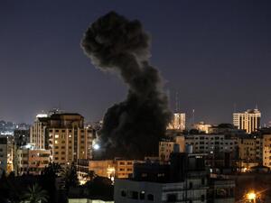 A plume of smoke billows above buildings during an Israeli airstike on Gaza City  (AFP)