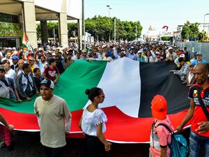 Protesters chant slogans and wave a giant Palestinian flag as they march in a demonstration in the Moroccan capital Rabat  (AFP)