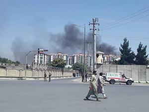 Afghan men walk on a road as smoke rises from the site of an attack in Kabul  (AFP)