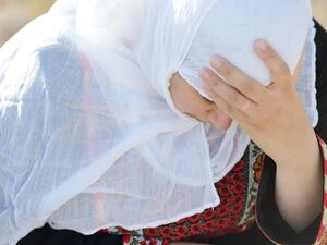 Desperate Arabic woman sitting on rock and crying (Shutterstock)