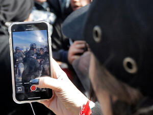 A woman films clashes in Beirut, Jan 2020 /AFP