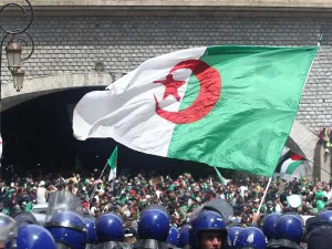 Algerian protesters wave a national flag as security forces stand guard during an an anti-government demonstration in Algiers on April 12, 2019. AFP