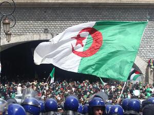 Algerian protesters wave a national flag as security forces stand guard during an an anti-government demonstration in Algiers on April 12, 2019. AFP