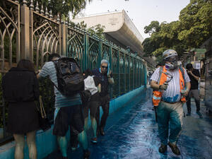 People react after being sprayed with blue-dyed water by a police riot-control vehicle during a protest outside the Kowloon Mosque in Hong Kong