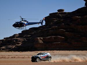 A helicopter flies as Russia's driver Vladimir Vasilyev and co-driver Vitaly Yevtyekhov of Ukrainia steer their Mini during the Stage 3 of the Dakar 2020 around Neom, Saudi Arabia