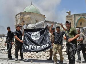 Iraqi Counter-Terrorism Service making the victory gesture as members hold the black ISIS flag upside down outside the destroyed Al-Nuri Mosque. (Fadel Senna / AFP)