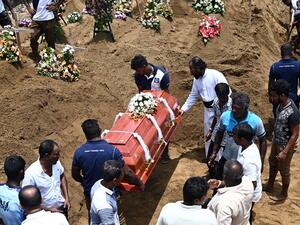 Relatives (R) watch as workers place the coffin of a bomb blast victim during a burial ceremony at a cemetery in Negombo on April 23, 2019. (AFP/ File)