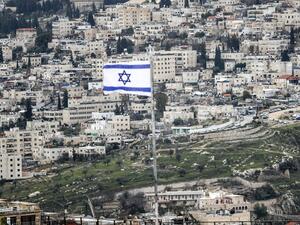 This picture taken on January 24, 2020 from the Mount of the Olives shows an Israeli flag flying (foreground) with the Jerusalem neighbourhood of Abu Tor seen in the background. AHMAD GHARABLI / AFP