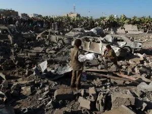 Yemeni civilians stand at the site of a Saudi air strike against Huthi rebels near Sanaa Airport on March 26, 2015 (AFP Photo/Mohammed Huwais)