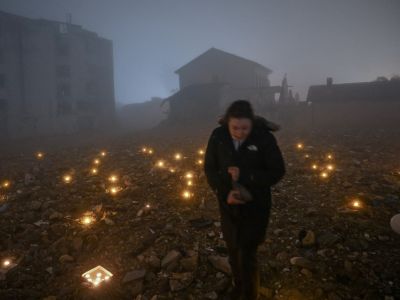 A woman leaves a candle at the site of a demolished building during the first anniversary of the earthquake, in Antakya on February 6, 2024. (Photo by Ozan KOSE / AFP) earthquake Turkey