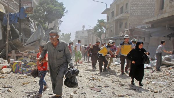 Members of the Syrian Civil Defence (known as the White Helmets) carry a wounded man on a stretcher (background) as people flee a bombarded neighbourhood following a reported air strike by pro-government forces on the town of Maaret al-Numan in the jihadist-held Idlib province on June 3, 2019. (Abdulaziz KETAZ / AFP)