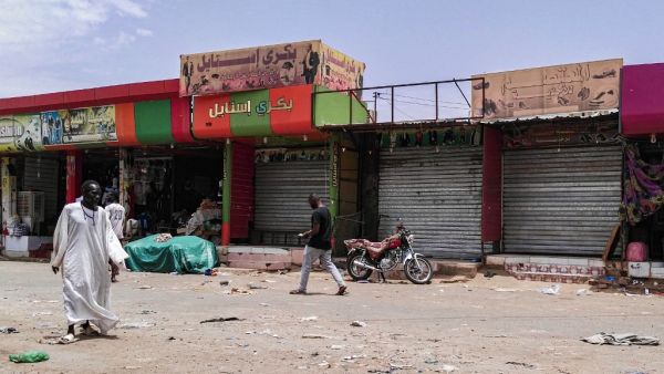 Sudanese men walk past closed shops in the capital Khartoum on June 11, 2019, on the third day of a civil disobedience campaign launched by protest leaders after a crackdown on a weeks-long sit-in left dozens dead on June 3. (AFP)