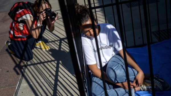 A photographer takes a picture of a teenager sitting in a cage during a protest of international labor groups, civil society and students against the policy of migrant family separation along the US-Mexico border on June 17, 2019 in front of the United Nations offices in Geneva. (FABRICE COFFRINI / AFP)