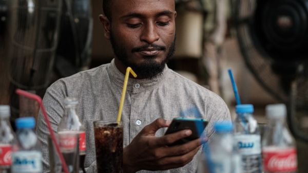 Sudanese Mohamed Omar, 25, uses his smart phone to access the internet a cafe in which an hour of internet costs 50 Sudanese pounds, which is approximately one US dollar, on June 17, 2019. (AFP/ File Photo)
