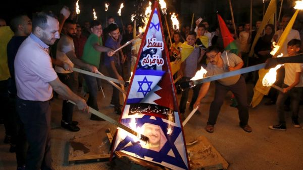 Palestinians burn a structure displaying the Israeli flag and a portrait of King Hamad al-Khalifa of Bahrain during protests against a US-led meeting this week in the Gulf kingdom on the Palestinian-Israeli conflict, in the West Bank city of Hebron on June 24, 2019. (AFP/ File Photo)