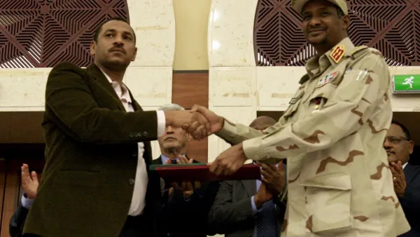 Sudanese deputy chief of the ruling miliary council Mohamed Hamdan Dagalo (R) and protest movement Alliance for Freedom and Changes leader Ahmad al-Rabiah shake hands after inking an agreement before African Union and Ethiopian mediators in Khartoum early on July 17, 2019. (AFP)
