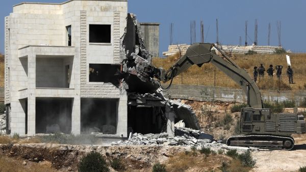 Israeli security forces tearing down one of the Palestinian buildings still under construction which have been issued notices to be demolished in the West Bank village of Dar Salah. (AFP/ File Photo)
