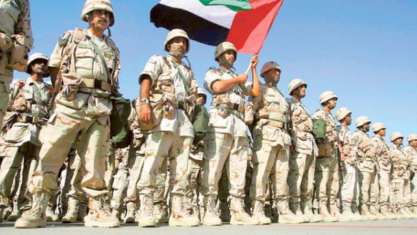 A contingent force from the United Arab Emirates holding their national flag, stand at ease on the tarmac of Kuwait International Airport upon their arrival here 23 February 2003. (AFP/ File Photo)