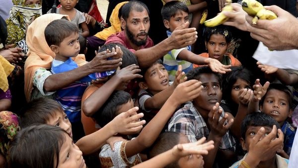 Rohingya refugees receive bananas from a Bangladeshi volunteer after crossing from Myanmar into Bangladesh at Shah Porir Dwip Island near Teknaf . (Tauseef Mustafa / AFP/Getty Images).