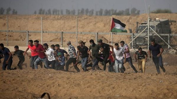 Palestinian demonstrators run away from the fence during protests along the border with Israel, east of Khan Yunis, in the southern Gaza Strip on July 12, 2019. (Mahmud Hams/AFP)