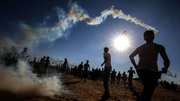 Palestinian youngsters use slingshots to hurl rocks at Israeli troops during clashes between Palestinian protesters and Israeli forces  (AFP)