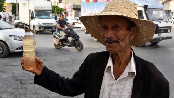 A street vendor holds a bottle of legmi, a coveted date palm drink, in the southwestern Tunisian town of Gabes on July 18, 2019. (AFP/ File Photo)