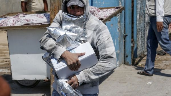 A Palestinian man transports food donations outside an aid distribution centre run by the United Nations Relief and Works Agency (UNRWA) in the central Gaza Strip refugee camp of Bureij (AFP)