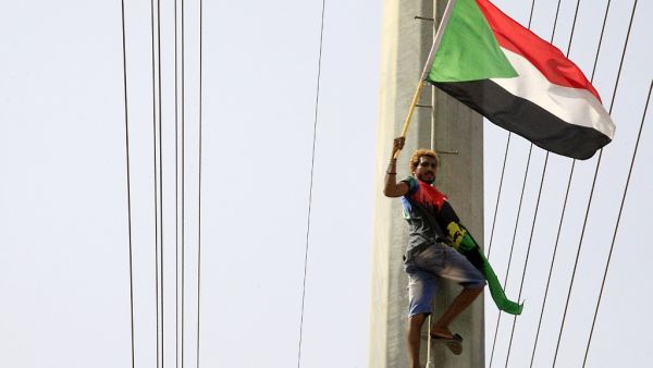 A Sudanese demonstrater waves his national flag in front of the Algerian embassy as people celebrate in Khartoum (AFP)