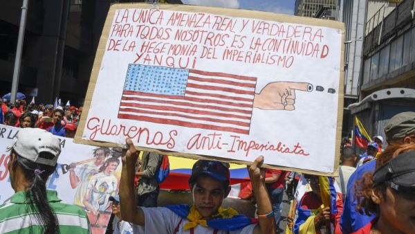 Holding up a sign with a slogan against US, a pro-government protester participates in a demonstration against US sanctions in Caracas on August 7, 2019. (AFP/ File Photo)