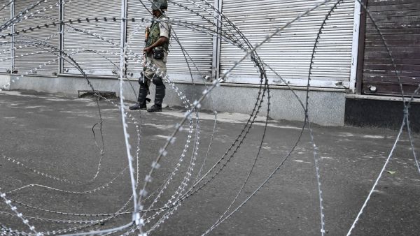 A security personnel stands guard behind a barbed fence wire during a lockdown in Srinagar (AFP)
