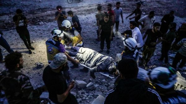 Members of the Syrian Civil Defence, also known as the "White Helmets", carry away on a stretcher a man rescued from the rubble of a collapsed building following a reported air strike in Kfar Ruma in Syria's northwestern Idlib province, on August 16, 2019. (AFP)