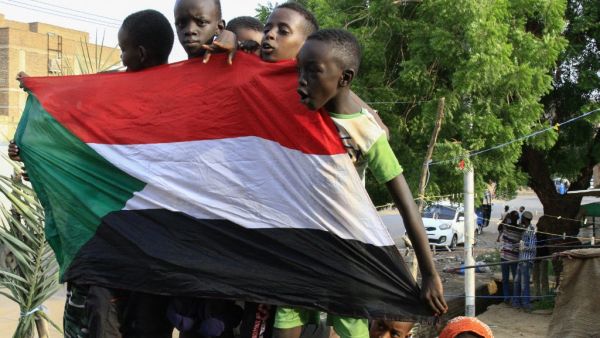 Young Sudanese boys carry a national flag as they celebrate in Bahri, the capital Khartoum's northern district (AFP)