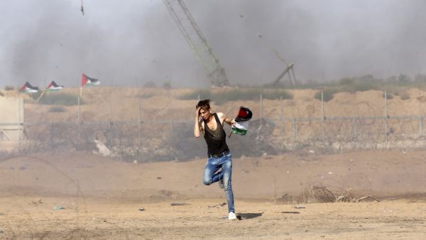 A Palestinian man runs for cover during clashes between Palestinian protesters and Israeli forces across the barbed-wire fence. (AFP/ File Photo)