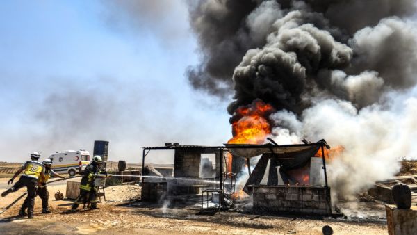 Firefighters from the Syrian Civil Defence, also known as the "White Helmets", extinguish a fire at a vehicle gathering point for fleeing civilians, which was hit by reported government forces' bombardment, in Maar Shurin . (AFP/ File Photo)