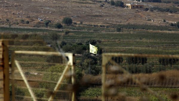 Northern Israeli town of Avivim shows a Hezbollah flag in the Lebanon village of Aitaroun (AFP)