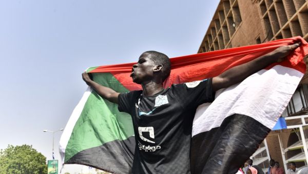 A Sudanese man spreads a national flag in Omdurman as he takes part in a rally in solidarity with Ahmed al-Kheir, a young Sudanese who died in custody after his arrest in January on allegations of organising anti-Bashir protests, on August 28, 2019. (AFP/ File Photo)