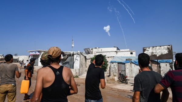 Men watch as tear gas canisters fired by the Turkish gendarmerie fall amidst clashes in a demonstration by displaced Syrians along the border with Turkey near the town of Atme in the northwestern Idlib province on August 30, 2019. (AFP/ File Photo)