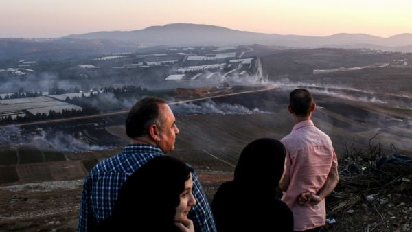 People watch as fires blaze along the Lebanese side of the border with Israel in the Lebanese village of Maroun al-Ras (AFP)