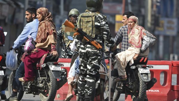 Indian paramilitary troopers stop Indian Kashmiri motorcyclists during a strict curfew in Lal Chowk (AFP)