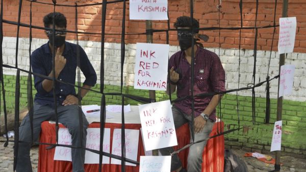 Kashmiri students shows their fingers with red mark as they sit inside a prop cage during a sit-in demonstration against the Indian government's move to revoke the special autonomy of the region guaranteed under Article 370 and 35A, in New Delhi on September 10, 2019. (Sajjad HUSSAIN / AFP)