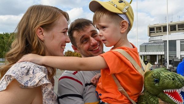 A former prisoner hugs his wife and child after he disembarked from a plane in Ukraine. Relations deteriorated between the two countries in 2014 (AFP)