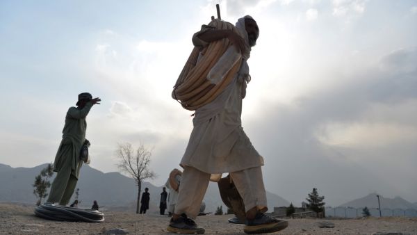 An Afghan labourer carries pipes and equipment on Nadir Khan hill overlooking Kabul on October 1, 2019. (Sajjad HUSSAIN / AFP)
