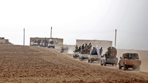A convoy of pickup trucks transports Turkey-backed Syrian fighters on the road between the Syrian towns of Tal Abyad and Kobane (AFP)