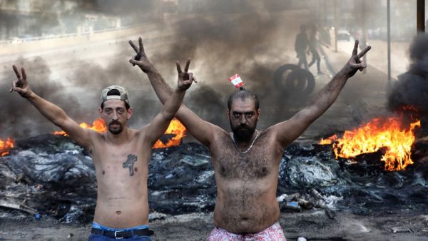 Lebanese demonstrators gesture as tires burn during a protest against dire economic conditions in the industrial zone of Dora on the northern outskirts of Beirut (AFP)
