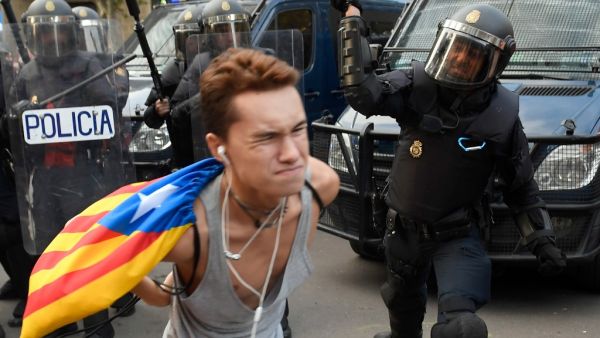 A Spanish national police officer uses his club to hit a protester during a demonstration called the Catalan pro-independence left youth group 'Arran' (AFP)